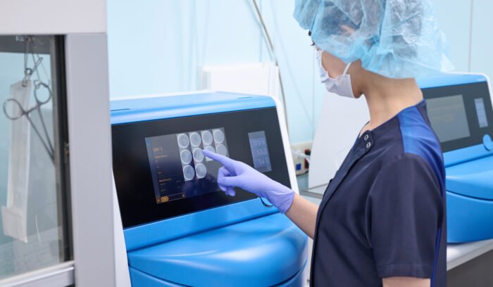 An embryologist in a modern laboratory uses an incubator for embryo cultivation.