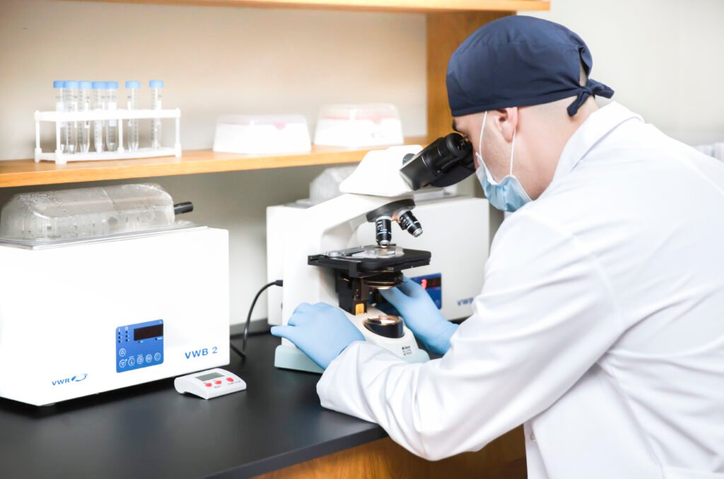 An andrologist at ReproART clinic analyzing sperm under a microscope in sterile laboratory conditions as part of male fertility assessment