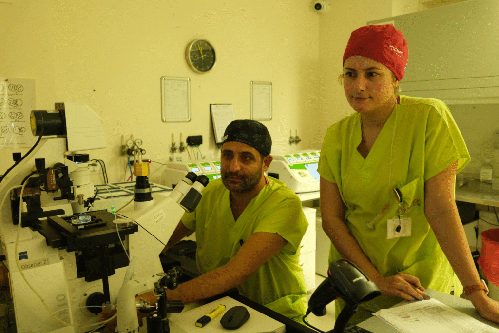 Two embryologists at British Cyprus IVF clinic working with a microscope in the laboratory during the in vitro fertilization process.