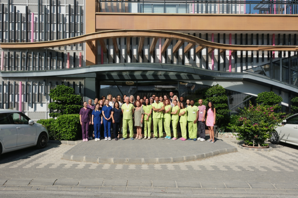 Large group of employees posing in front of the British Cyprus IVF clinic, representing the professional IVF team.