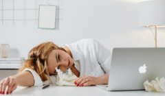 Exhausted woman resting her head on a table, symbolizing stress while balancing fertility treatment and work responsibilities