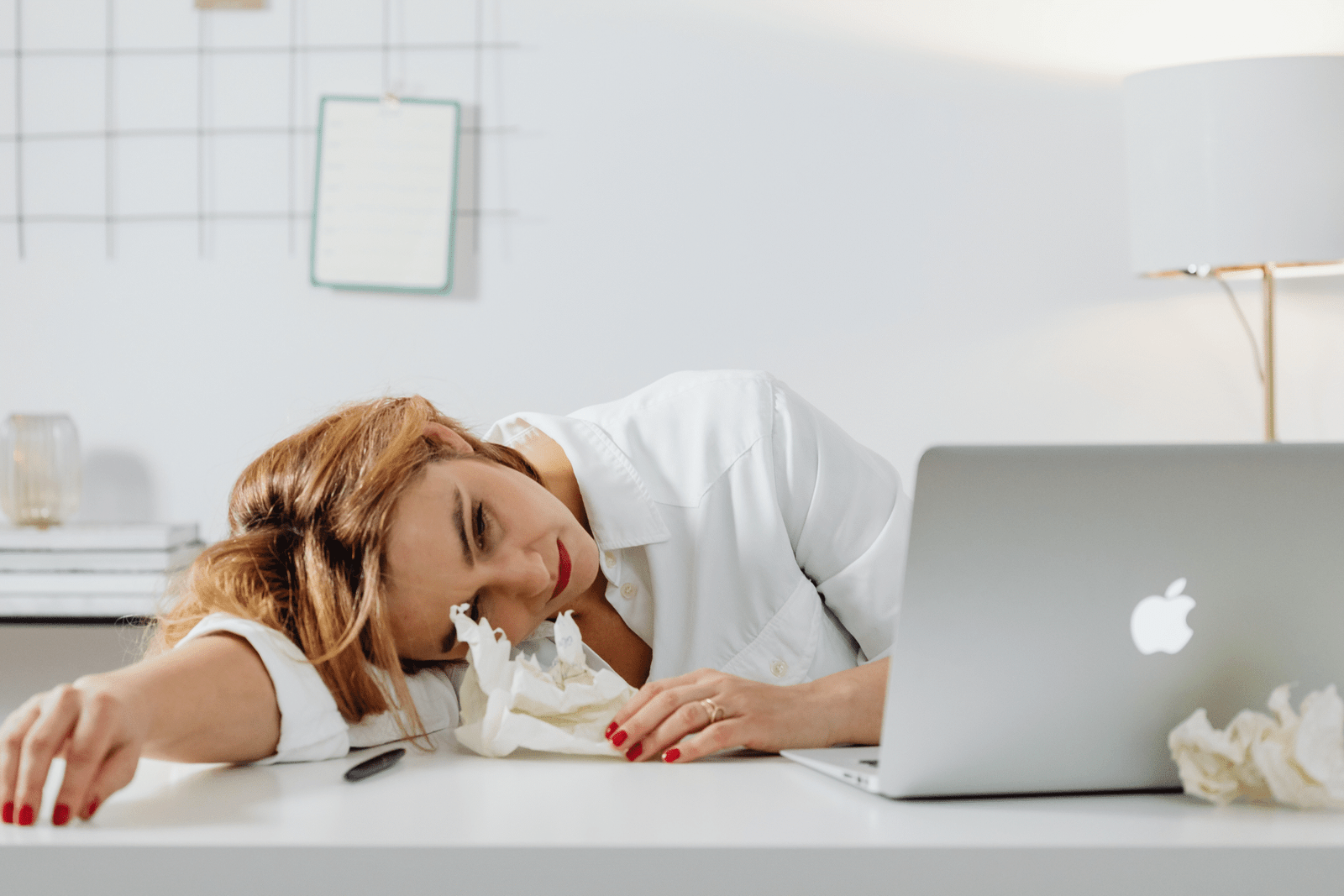 Exhausted woman resting her head on a table, symbolizing stress while balancing fertility treatment and work responsibilities